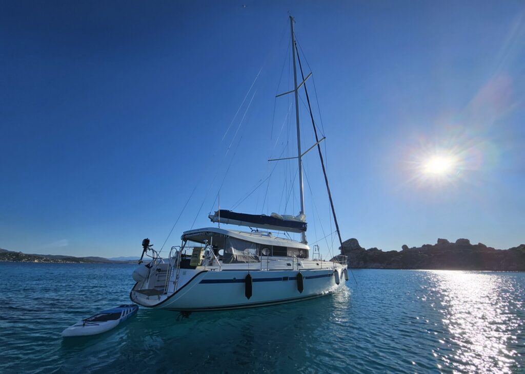 Voilier Atoll Dufour 50 dans les eaux turquoises avec un soleil brillant au milieu du ciel bleu